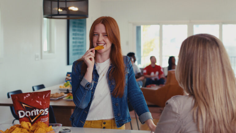 woman eating a doritos chip and winking