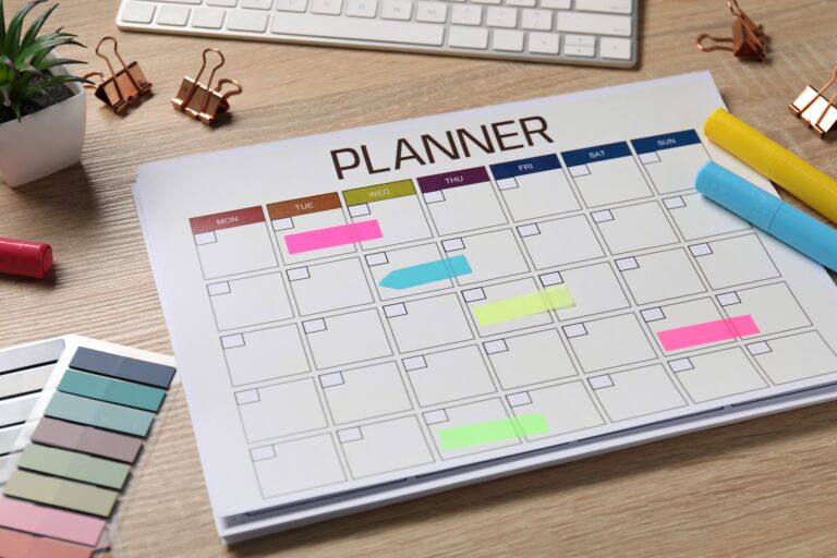 Planner and stationery on wooden desk, closeup