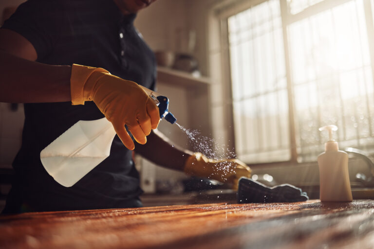 Shot of an unrecognisable man disinfecting a kitchen counter at home.