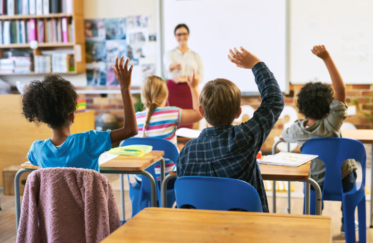 students raising their hands in a school classroom